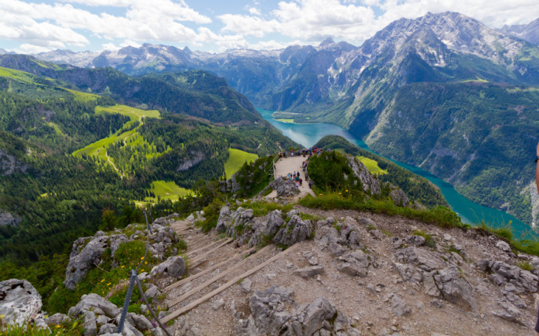 Des Naturparadies Königssee, gesehen vom Jenner aus, mit steilen Bergwänden, üppigem Grün und dem blauen Wasser des Sees im Tal.