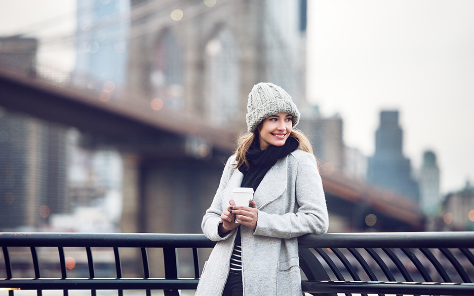 Frau mit Winterkleidung auf Br&uuml;cke mit Kaffee