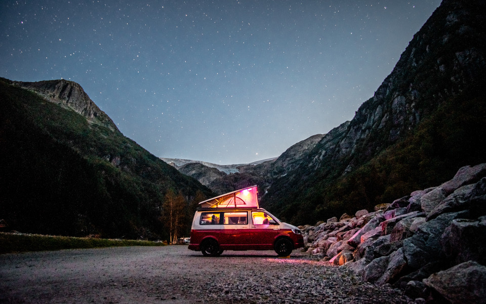VW Bulli mit Aufstelldach unter Sternenhimmel in Norwegen