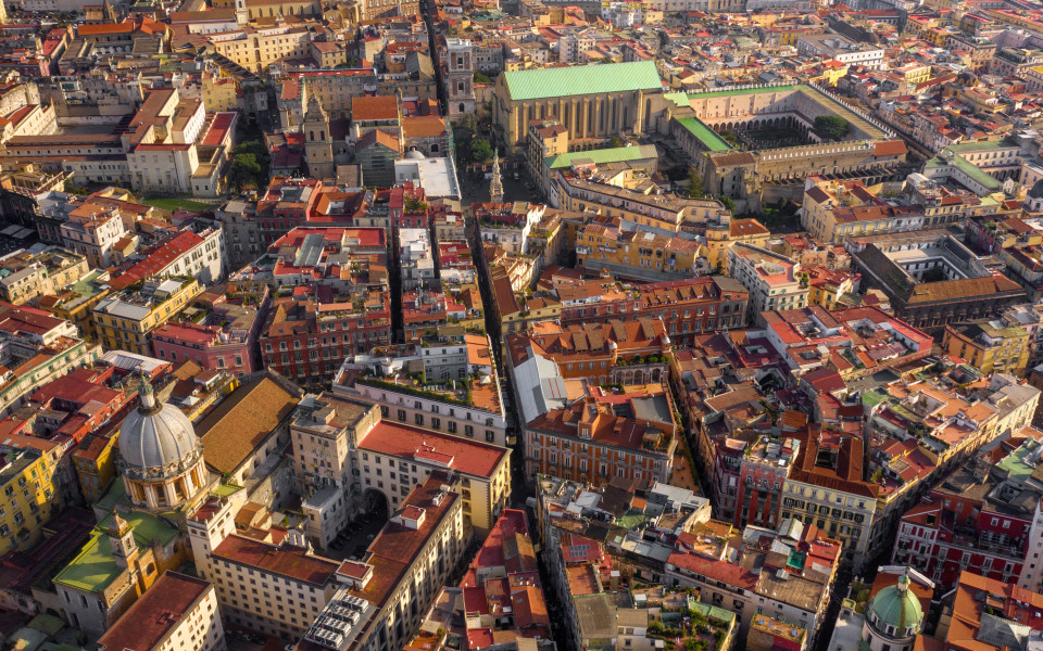 Vogelperspektive auf die Spaccanapoli, die sich schnurgerade durch das historische Zentrum von Neapel zieht, flankiert von farbenfrohen Altbauten, Kirchen und Kl&ouml;stern.