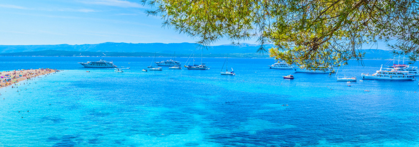 Bekannter Strand Zlatni Rat auf der Insel Brač in Kroatien mit türkisblauem Wasser, Yachten und Badegästen