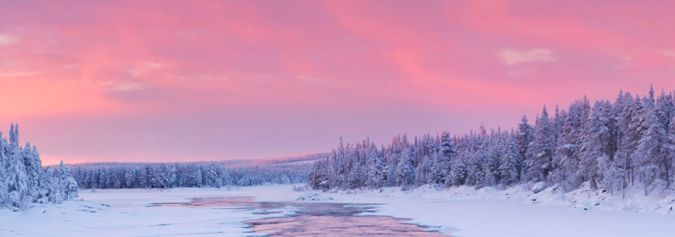 Sonnenaufgang über einem Fluss in einer Winterlandschaft, Finnisch-Lappland
